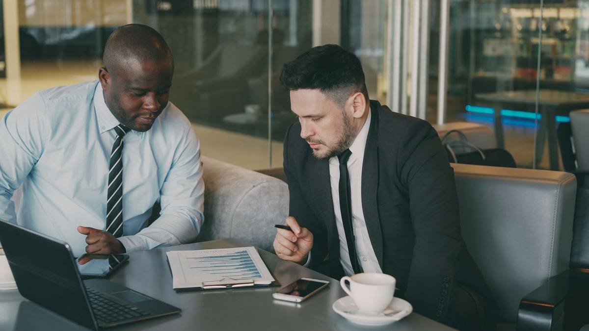 Two businessmen reviewing a report together with a laptop in a meeting