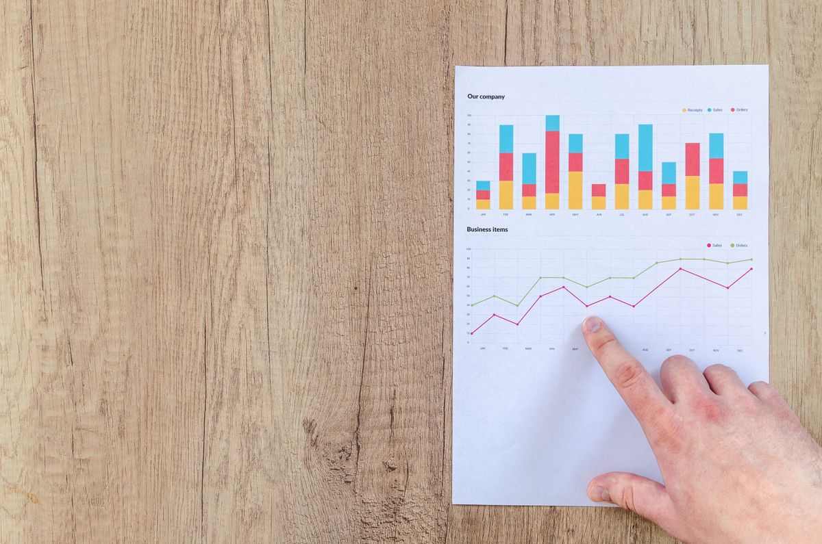 Printed marketing charts with a hand pointing at growth figures