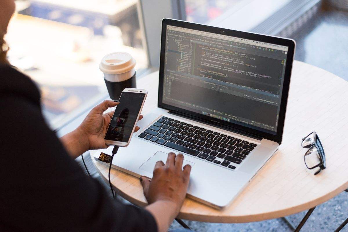 Person checking a website on a phone next to a laptop